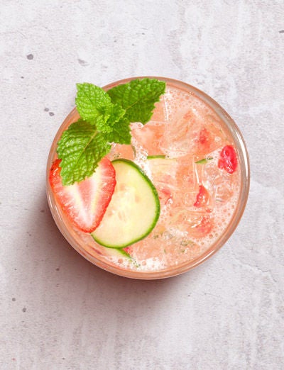 a glass of drink with strawberries and cucumber
